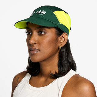 side view of the ciele athletics FTSCap unisex running hat with a curved brim in emerald color, on a model